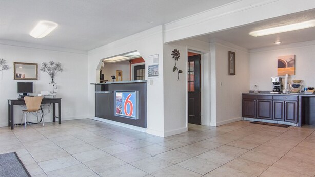Una hall d'albergo moderna con una reception, un piccolo angolo salotto e una piccola cucina.