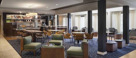 A modern hotel lobby with a bar area, seating arrangements, and a view of the outside.