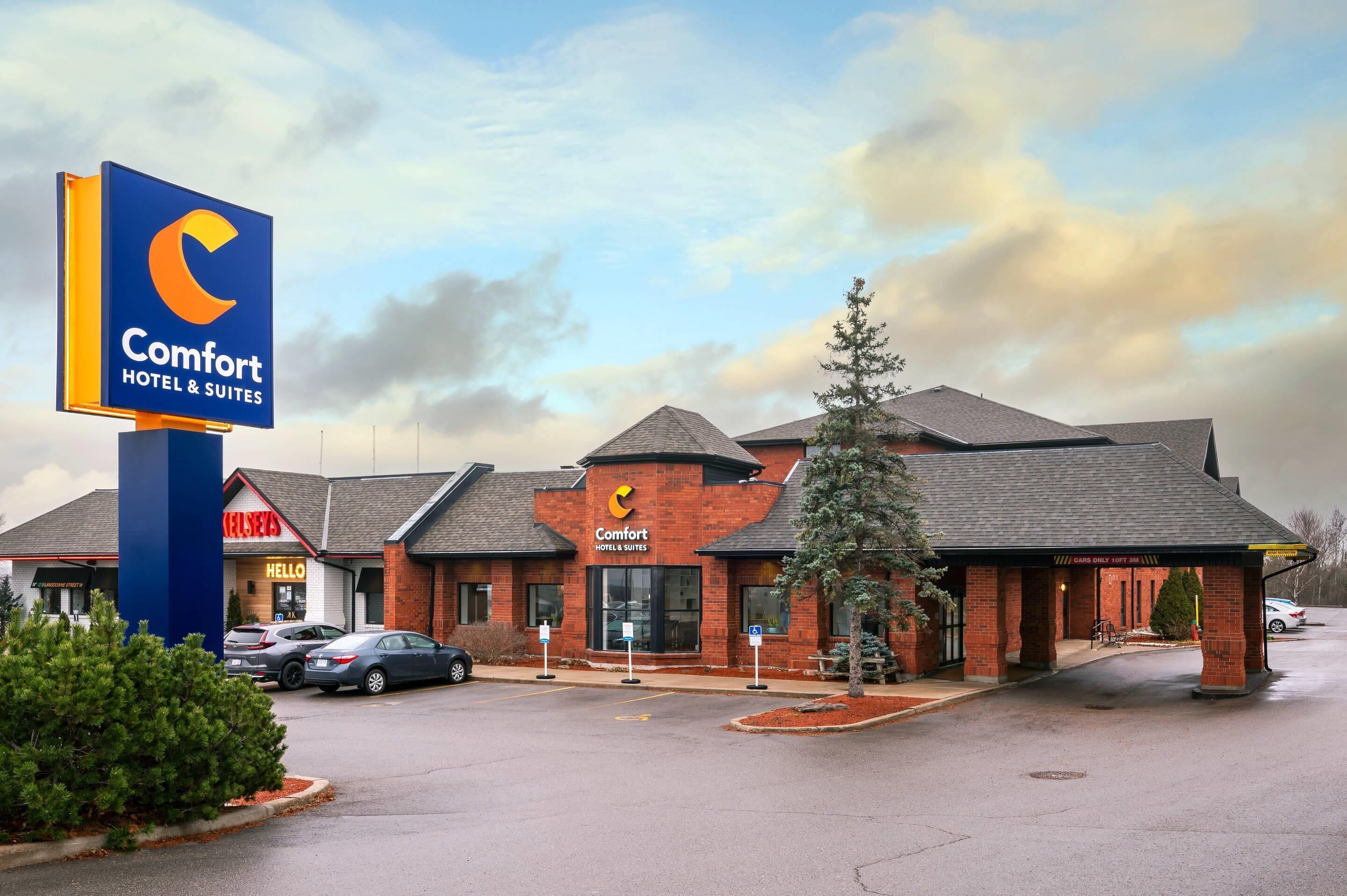 Un hôtel Comfort Hotel & Suites doté d’une enseigne bien visible, d’une façade en briques et d’un parking.