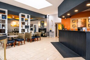 A modern hotel lobby with a reception desk, seating area, and a fireplace. - Comfort Hotel & Suites (Peterborough)