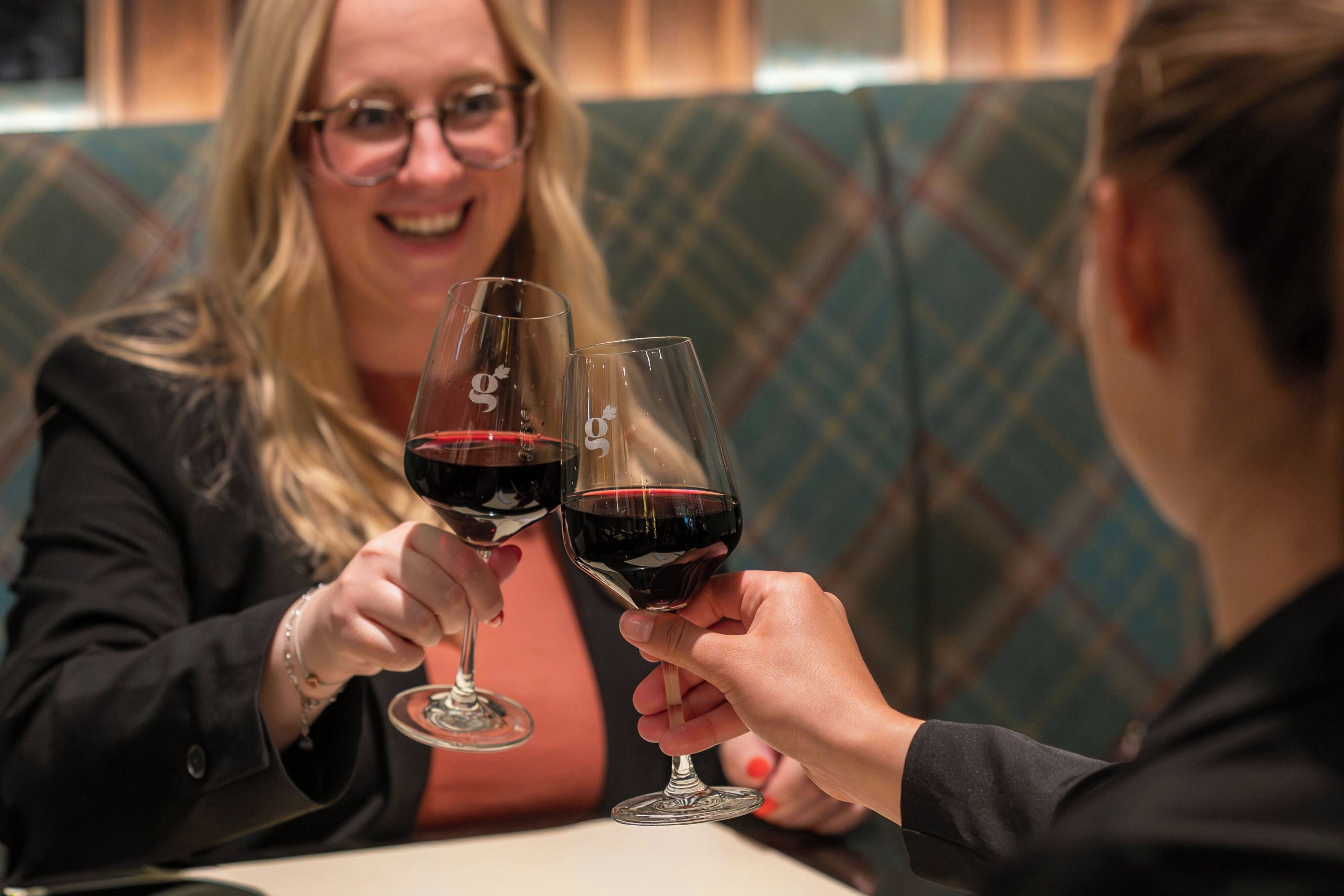 Two people toasting with wine glasses at a table.