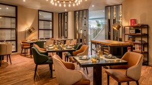 A modern dining area with a wooden table, leather chairs, and a chandelier. - Munich Marriott Hotel (Munich)