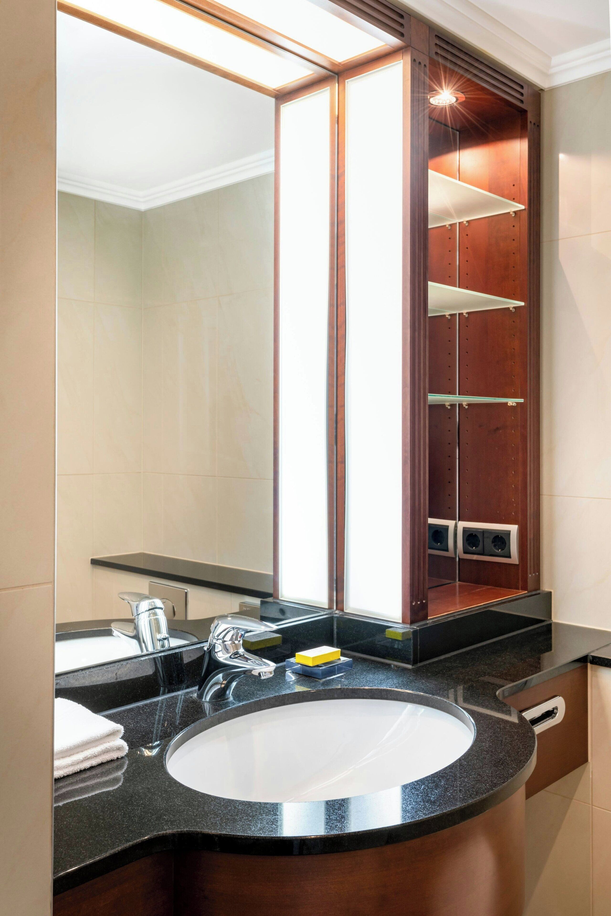 A bathroom with a large mirror, a sink, and a wooden vanity cabinet.