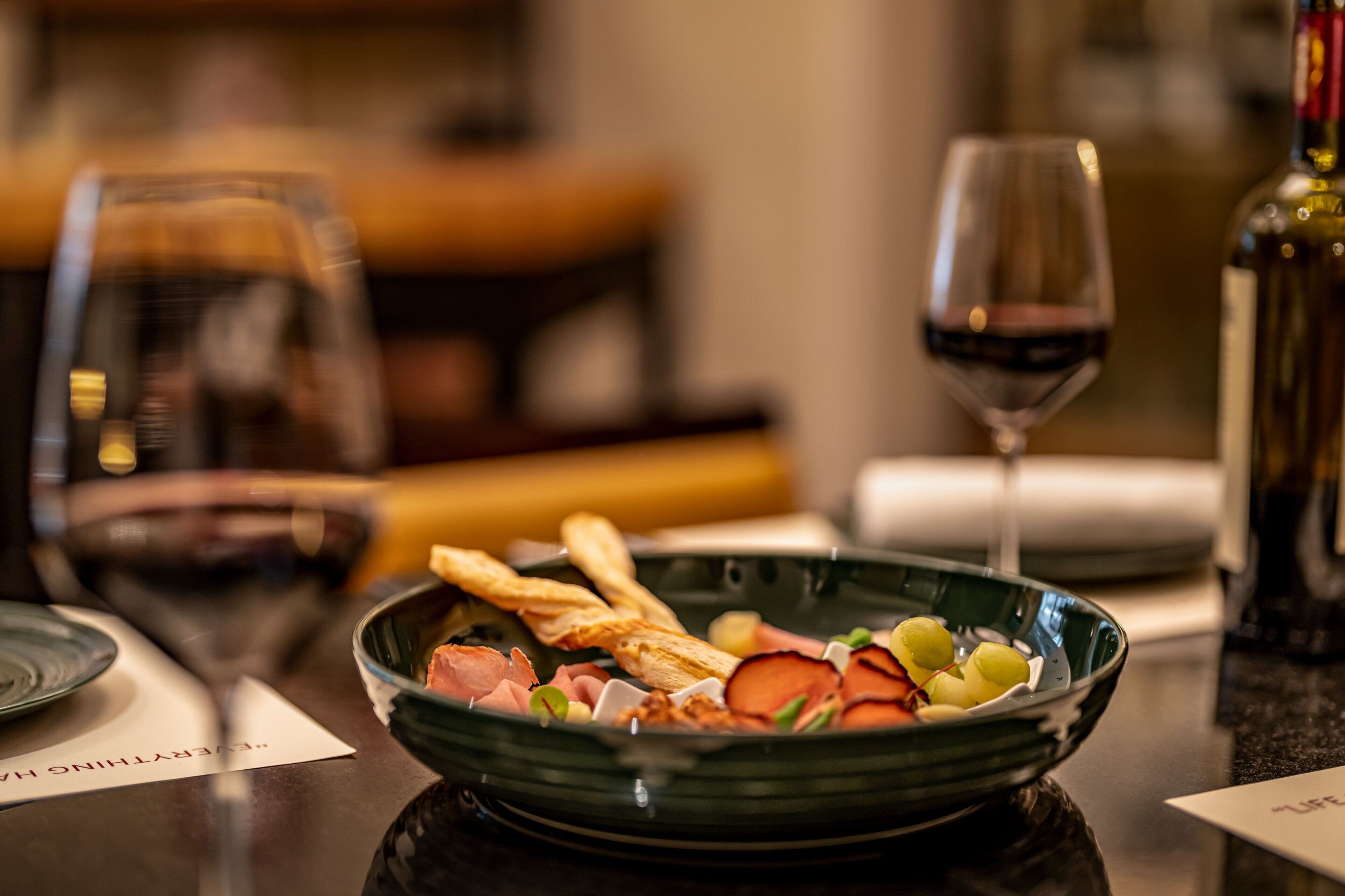 Una mesa de comedor con un bol de comida, una copa de vino y una botella.