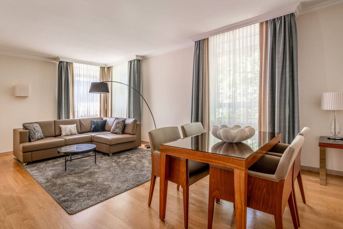 A modern living room with a sectional sofa, a glass dining table, and a floor lamp.