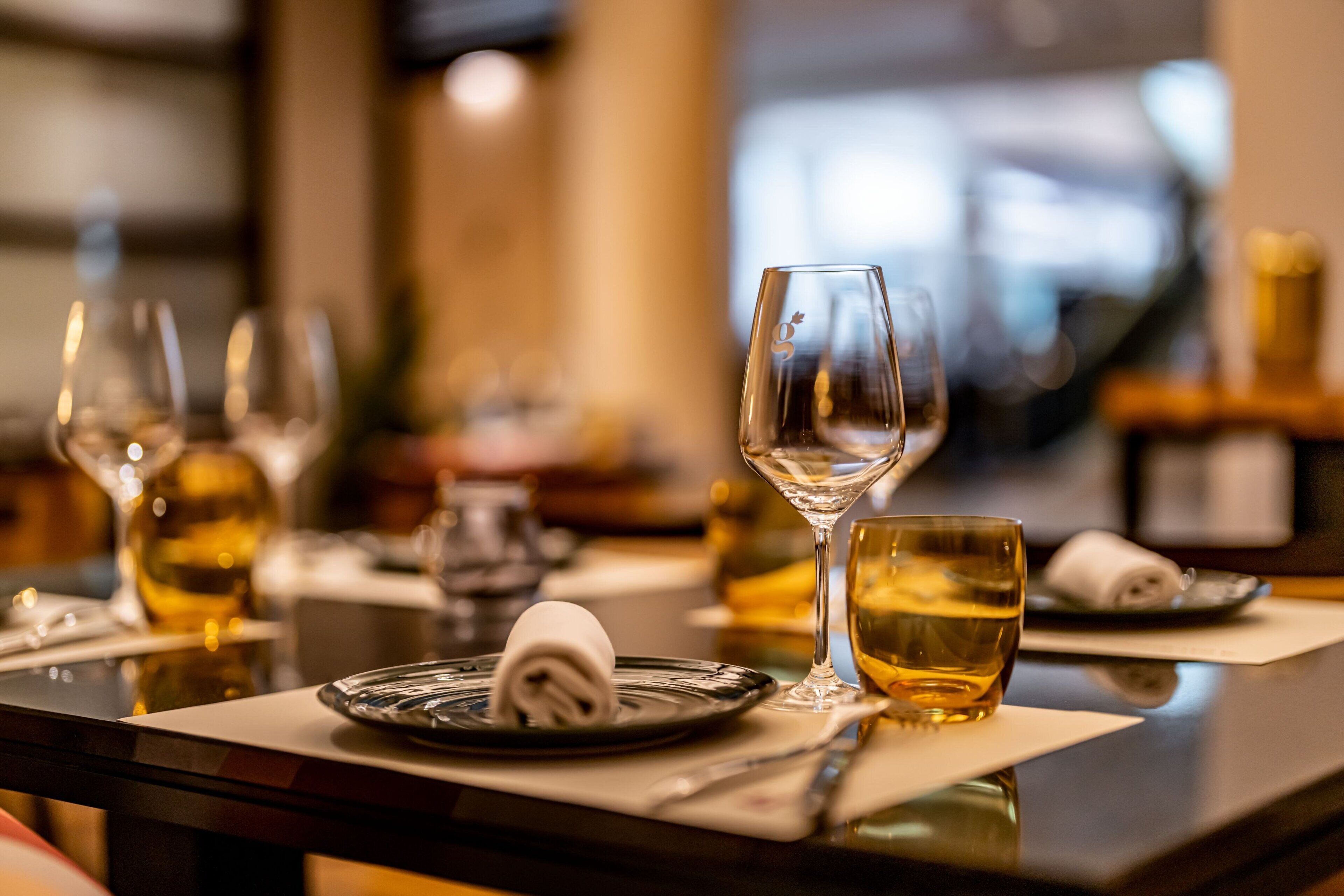 A dining table set with wine glasses, a folded napkin, and a glass of water.