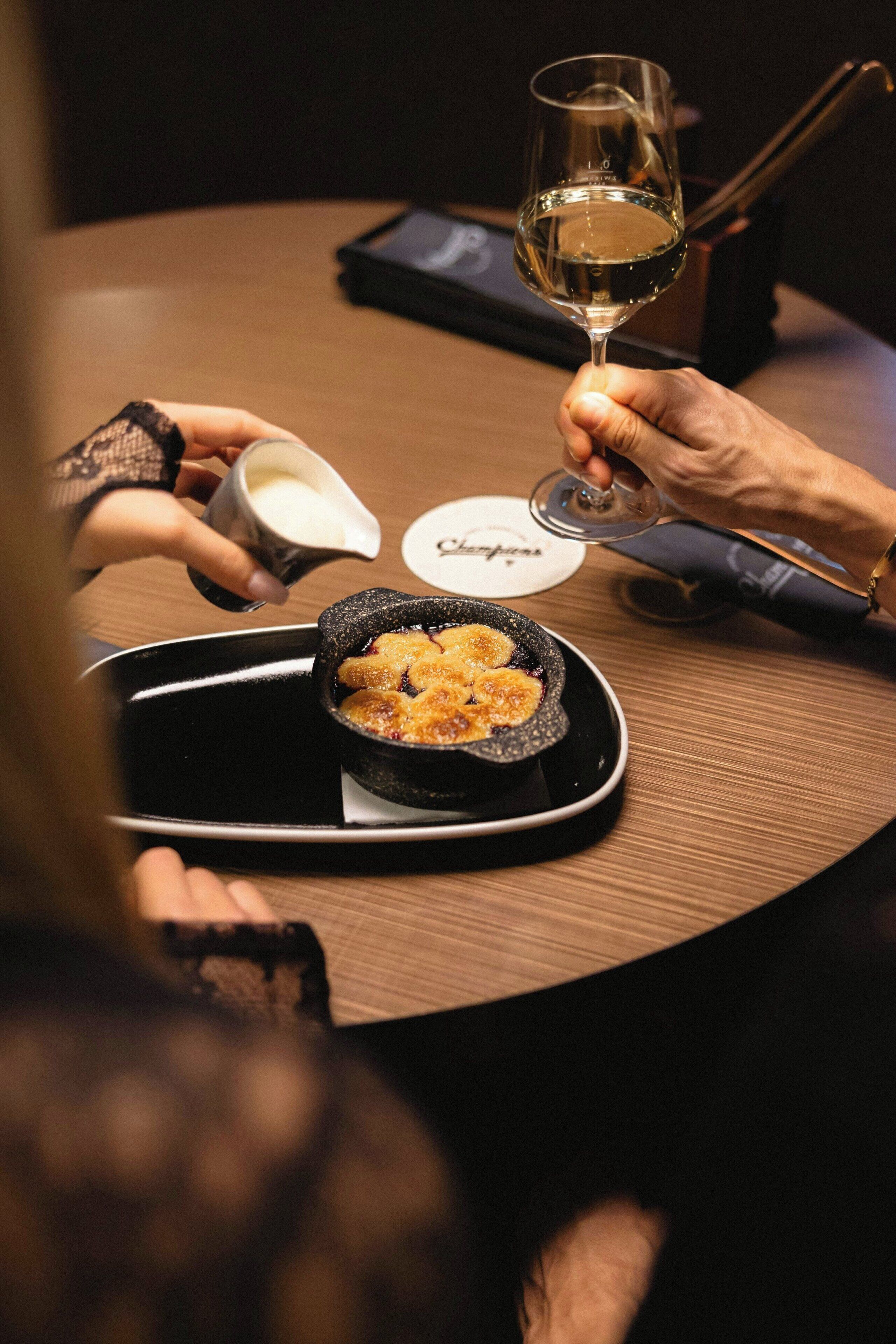 A person holding a wine glass and a small bowl of food on a tray.