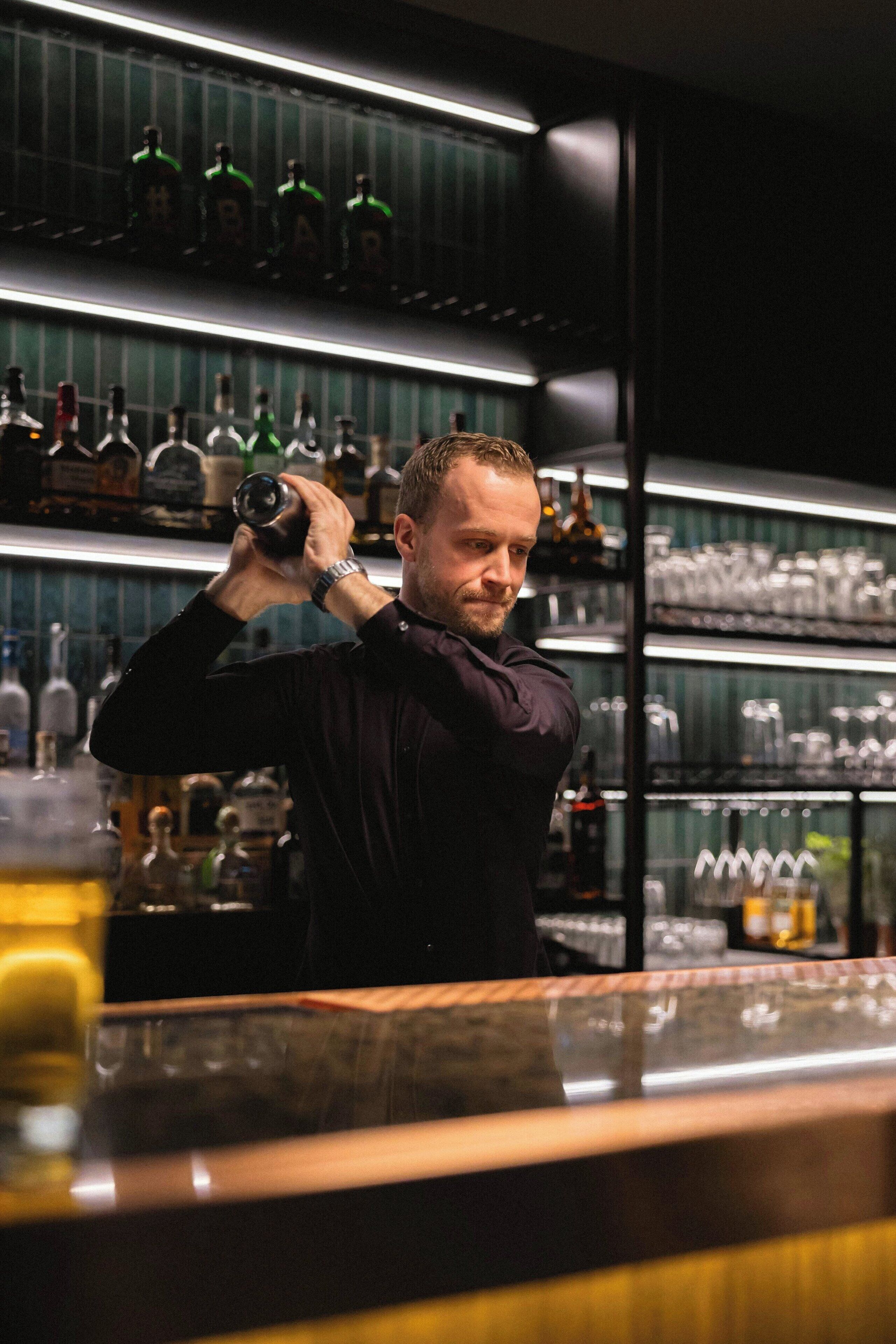 Un espace bar avec des étagères remplies de bouteilles et de verres.