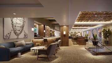 Un hall d’hôtel moderne avec un comptoir d’accueil, un espace salon et une grande œuvre d’art abstraite accrochée au mur.
