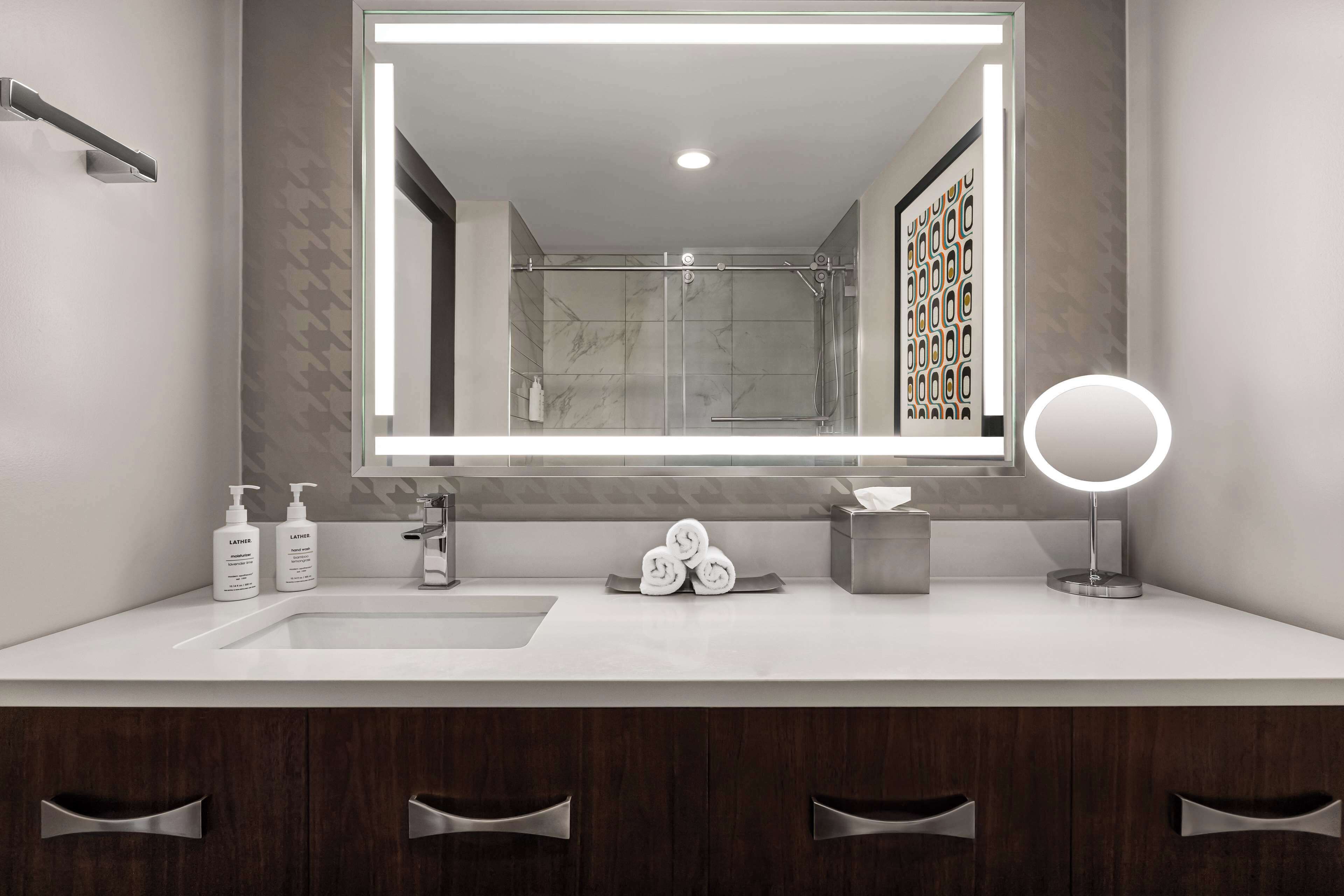 Een moderne badkamer met een grote spiegel, een wastafel en een douche.