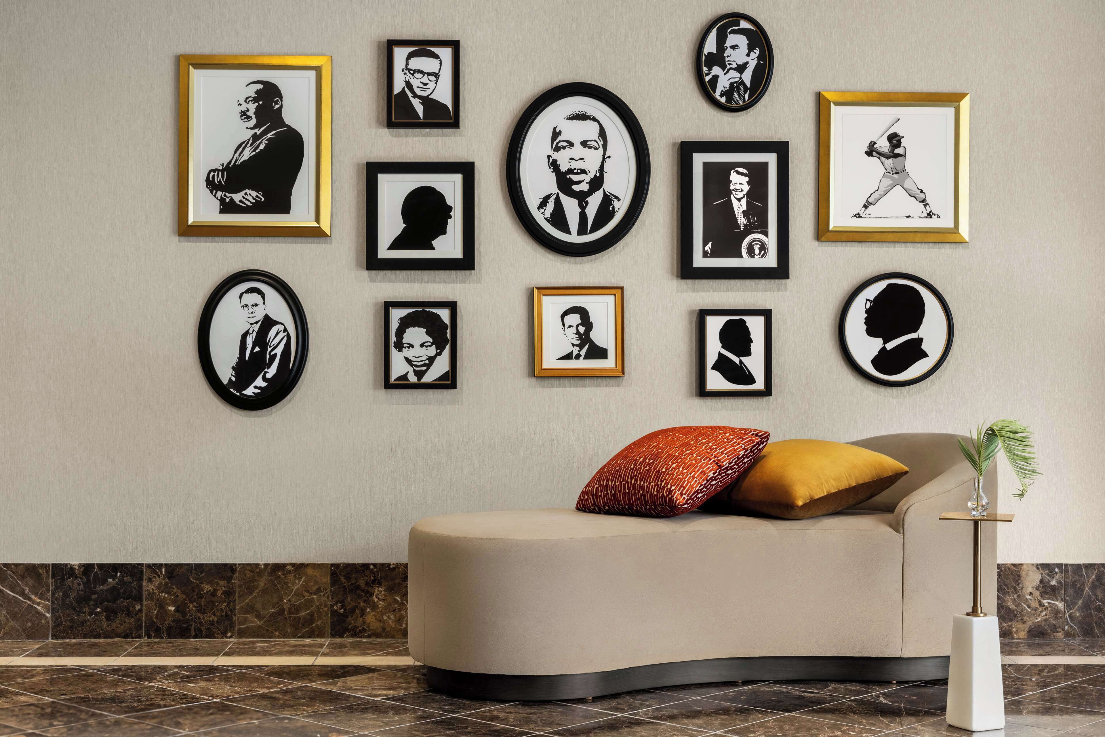 A modern living room with a curved sofa, a small side table, and a framed portrait collection on the wall.