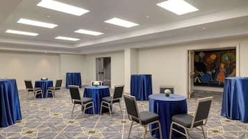 A conference room with round tables, chairs, and a patterned carpet.