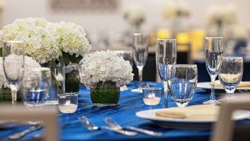 A table set with white flowers, clear glasses, and a blue tablecloth.