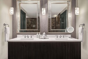 Une salle de bain moderne avec un meuble-lavabo à deux vasques, deux miroirs fixés au mur et une douche visible au fond.