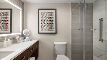 A modern bathroom with a white sink, a toilet, and a glass-enclosed shower.