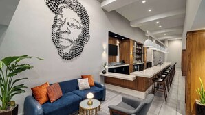 A modern living room with a blue sofa, a round coffee table, and a unique wall art piece. - The American Hotel Atlanta Downtown, Tapestry Collection by Hilton (Atlanta)