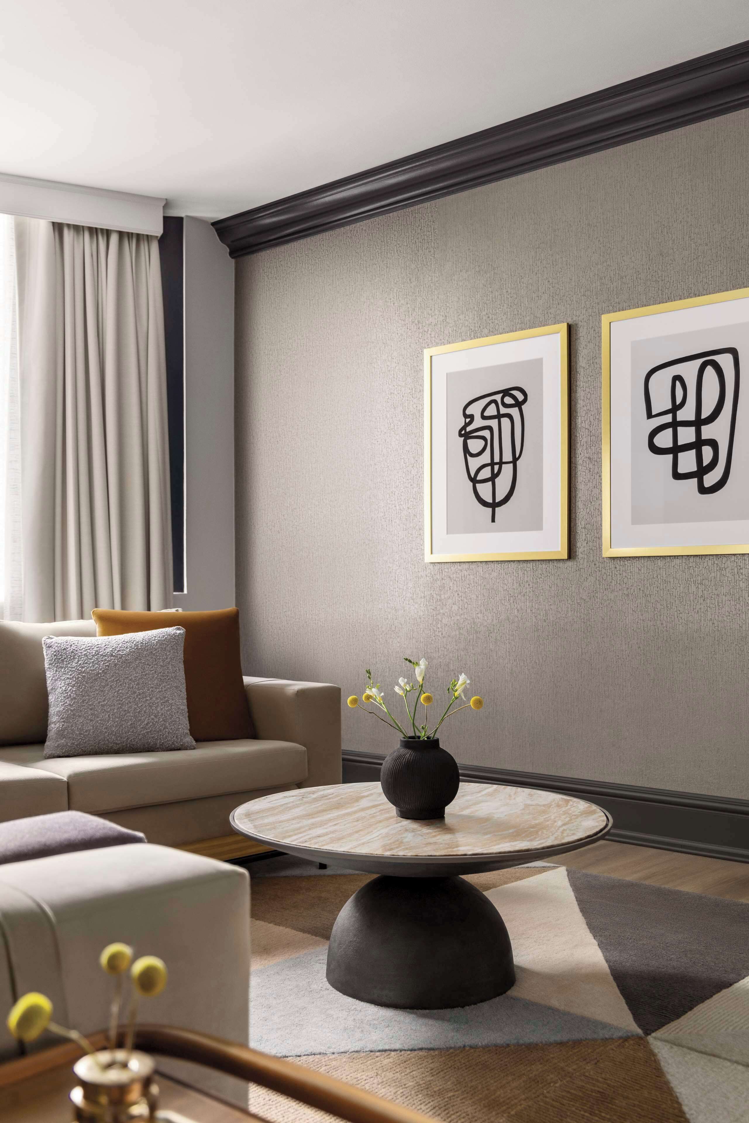 A modern living room with a sofa, a coffee table, and two framed abstract artworks on the wall.