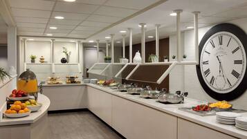 A modern buffet setup with a variety of food items, a large wall clock, and a clean, well-lit interior.