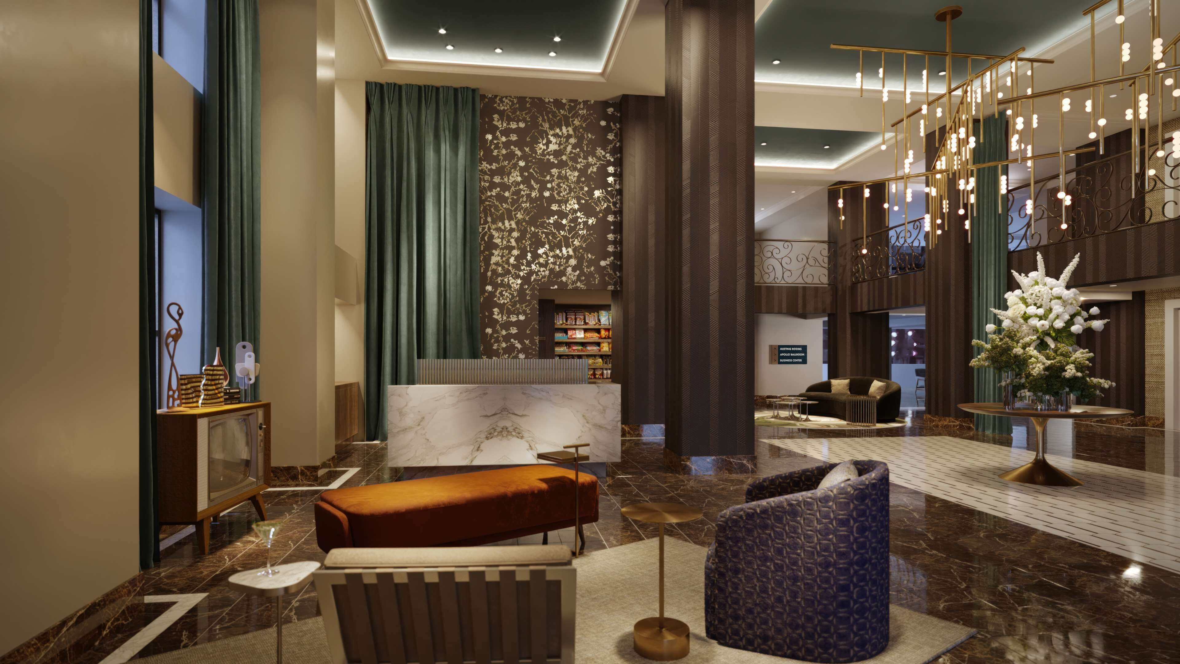 A modern lobby with a reception desk, seating area, and a staircase with decorative lighting.
