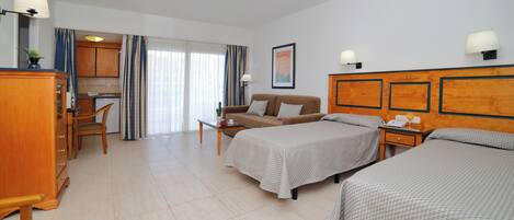 A hotel room with two beds, a sofa, a desk, and a kitchenette.