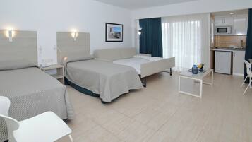 Habitación de hotel con dos camas, un sofá, una pequeña mesa de comedor y una kitchenette.