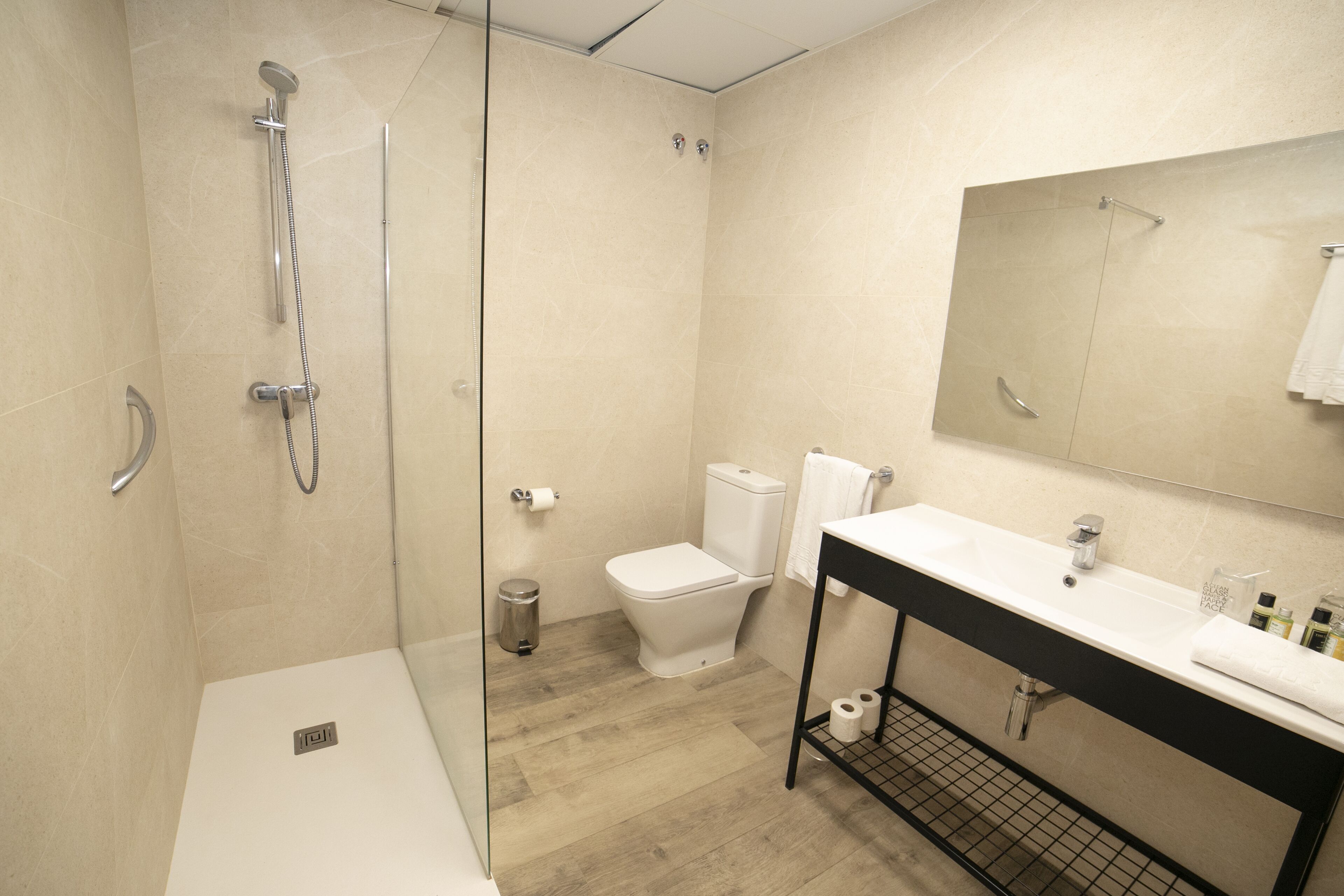 A modern bathroom with a glass-enclosed shower, a white toilet, and a black vanity with a mirror.