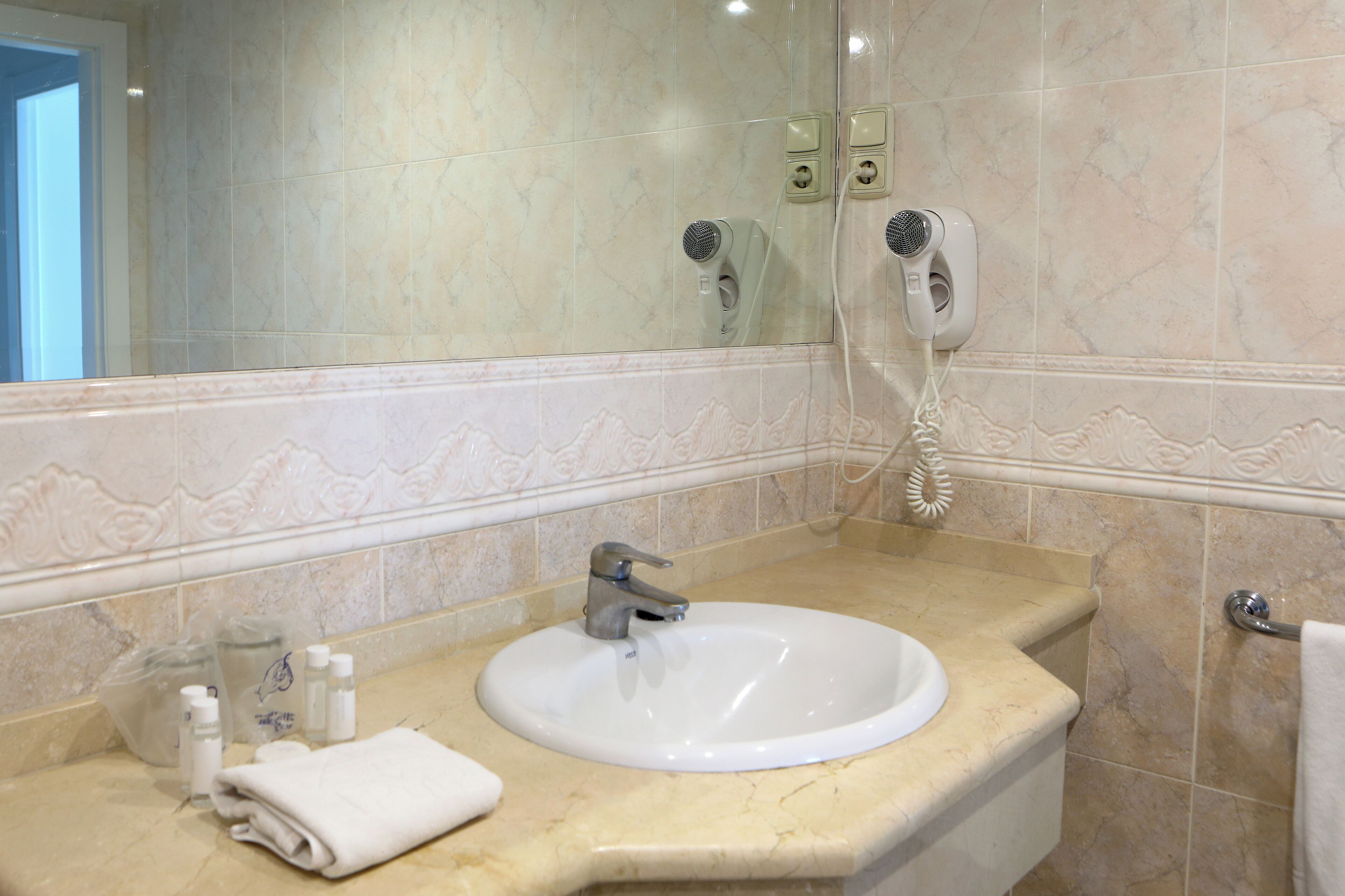A bathroom with a sink, mirror, and hairdryer.