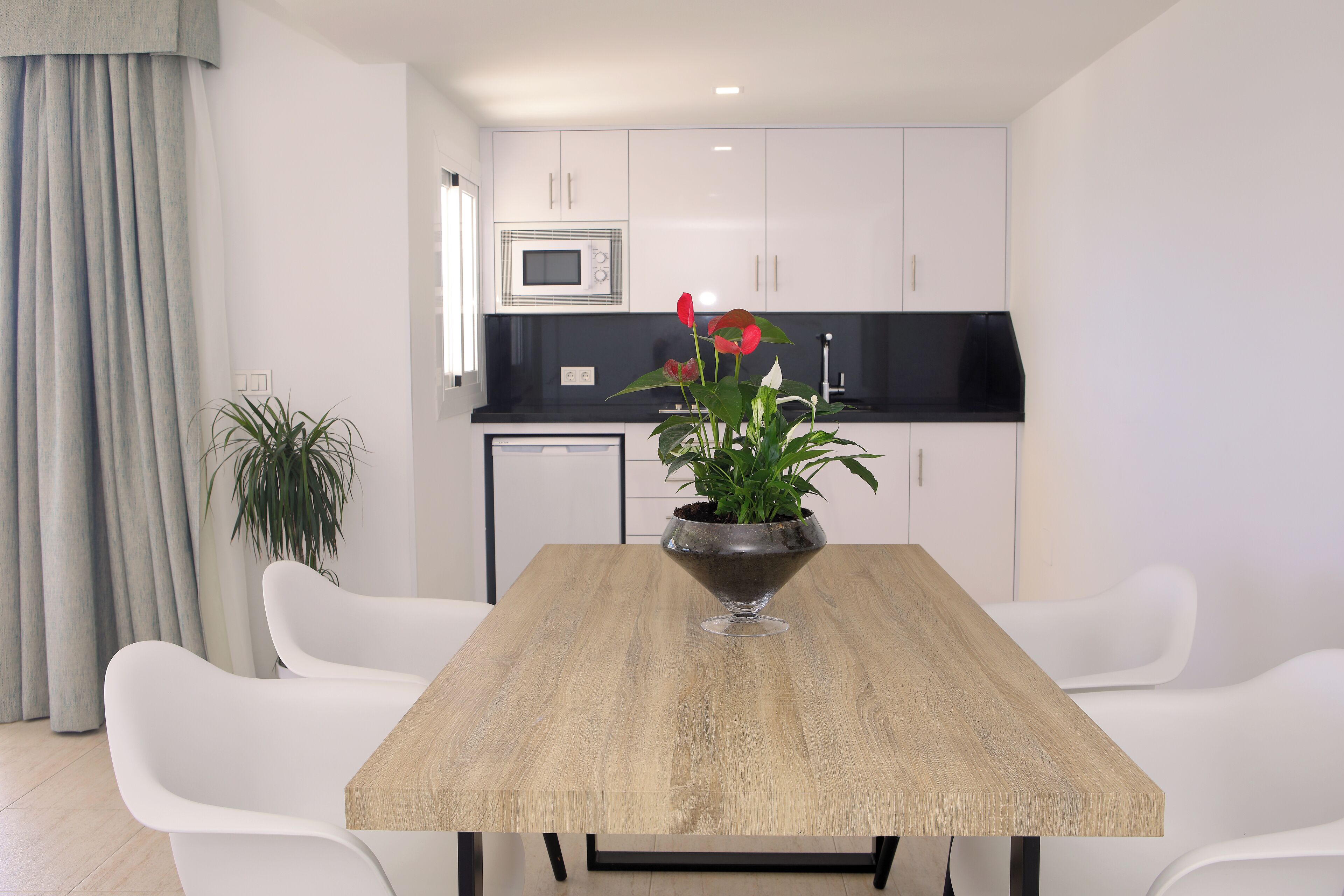 Een moderne keuken met witte kasten, een zwart aanrecht en een magnetron.