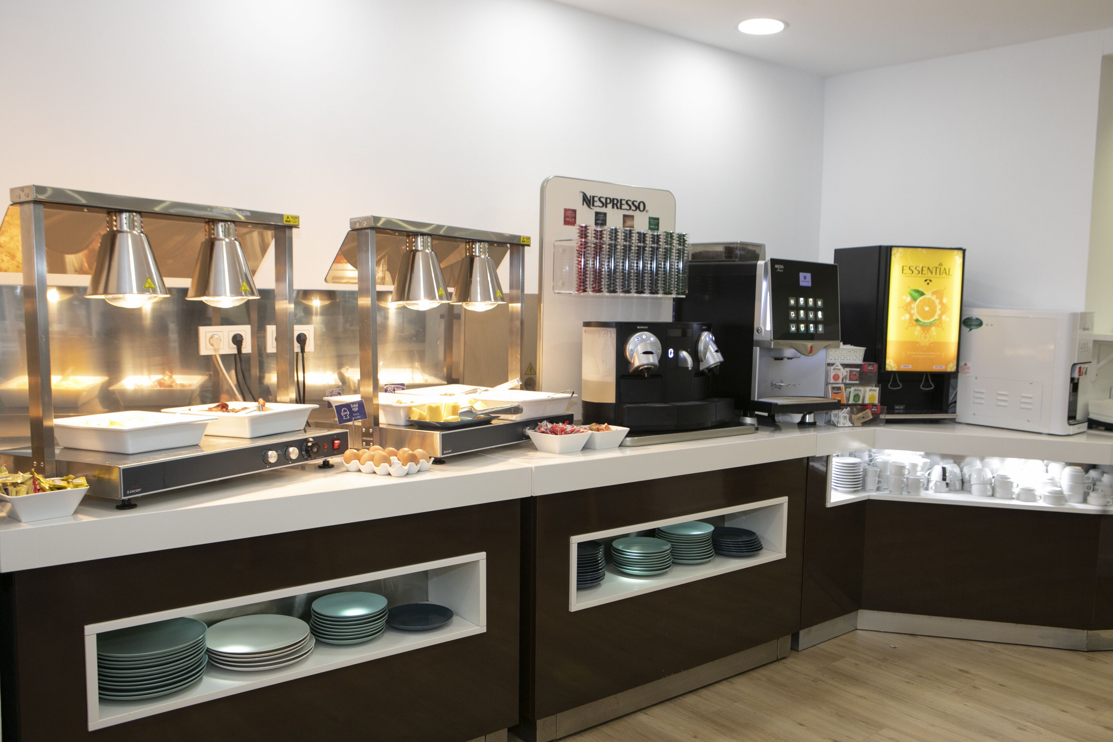 A buffet setup with various food stations, including a coffee machine and a refrigerator.