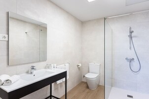Ein modernes Badezimmer mit großem Spiegel, schwarzem Waschtisch, Toilette und Duschkabine.