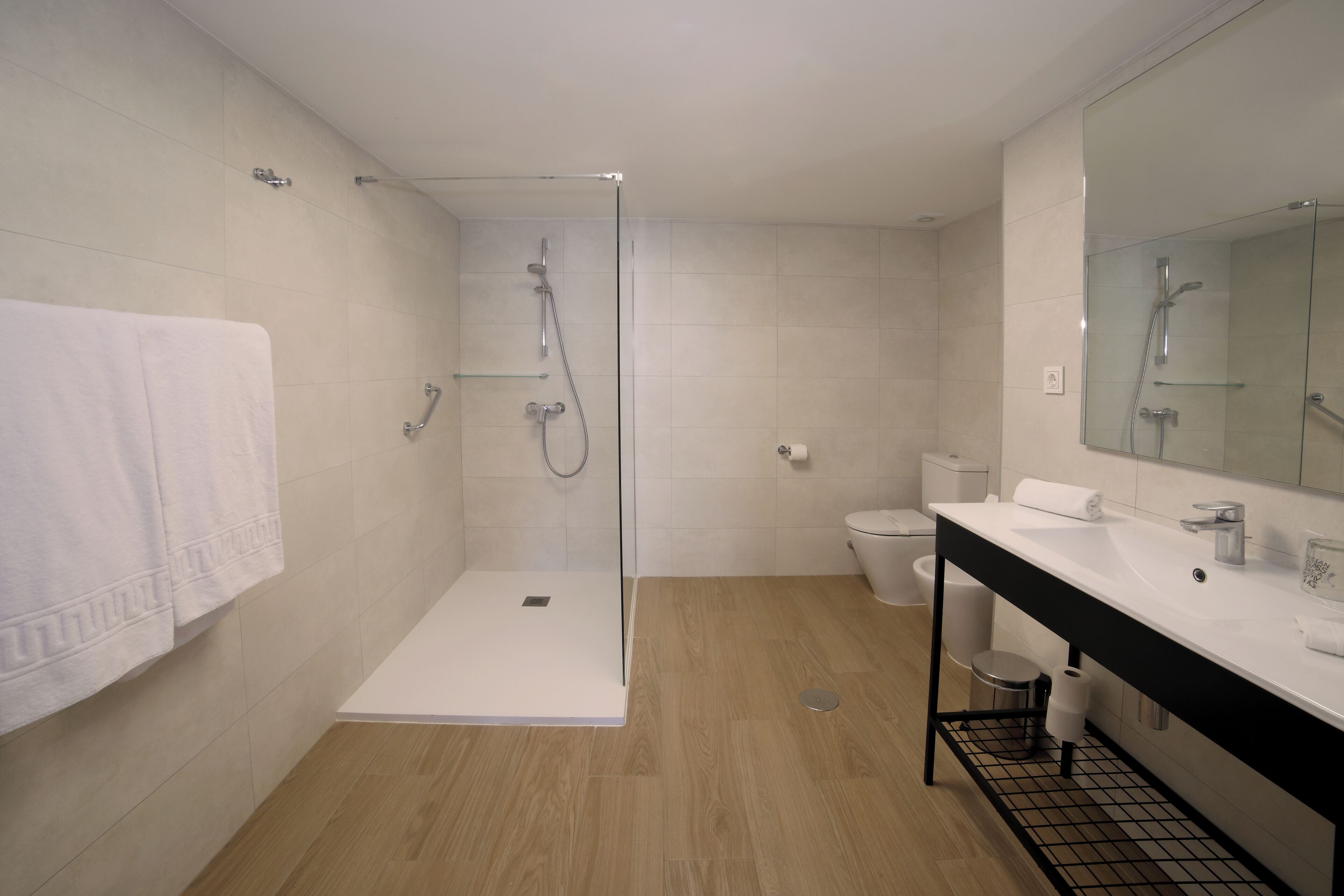 Un baño moderno con cabina de ducha de vidrio, un lavabo blanco y un inodoro.