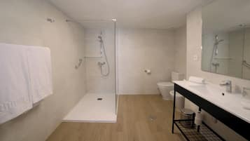 Un baño moderno con cabina de ducha de vidrio, un lavabo blanco y un inodoro.