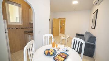 A dining area with a table set for breakfast, including croissants, eggs, and a fruit plate.