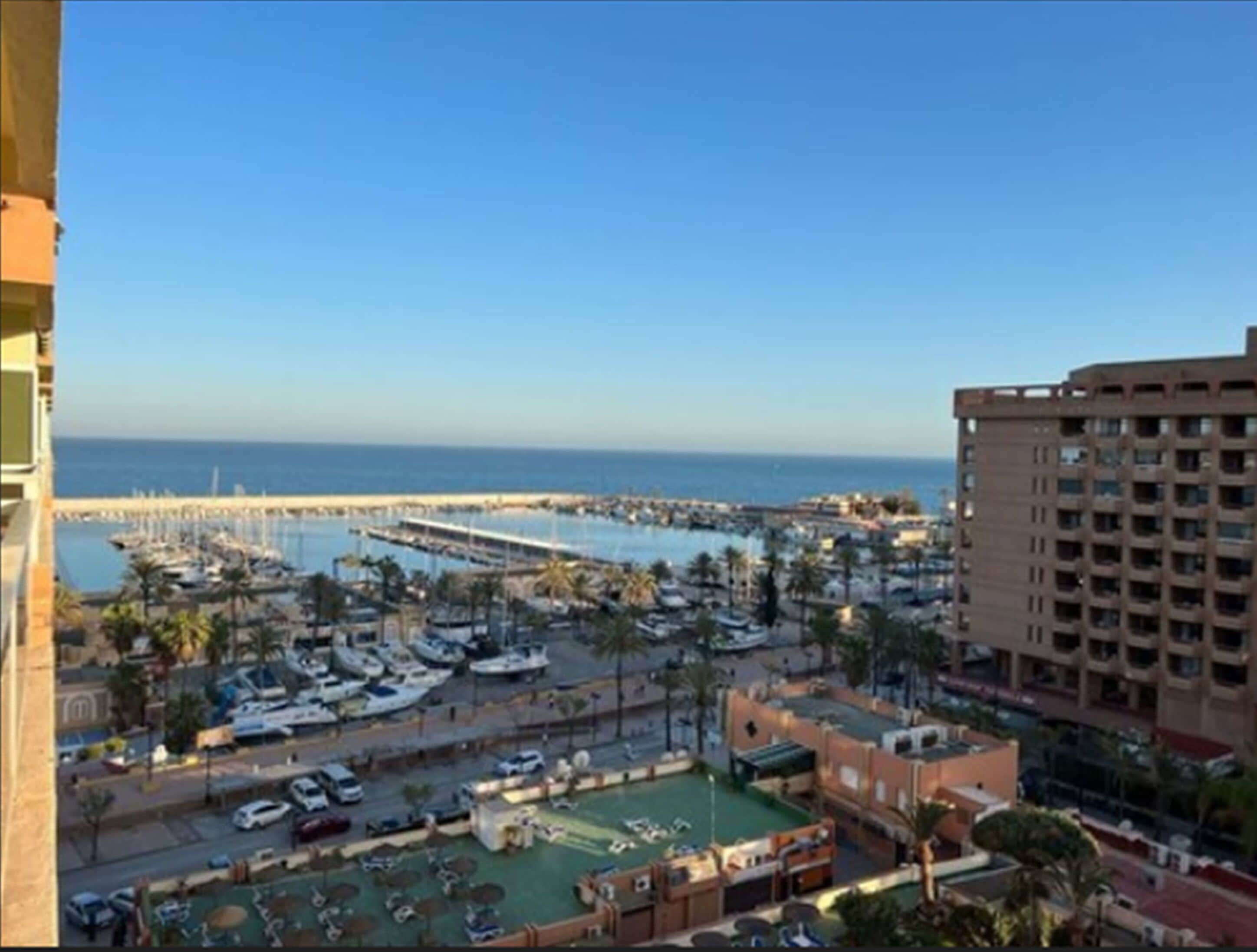 Puerto deportivo con barcos, piscina y vista al mar.