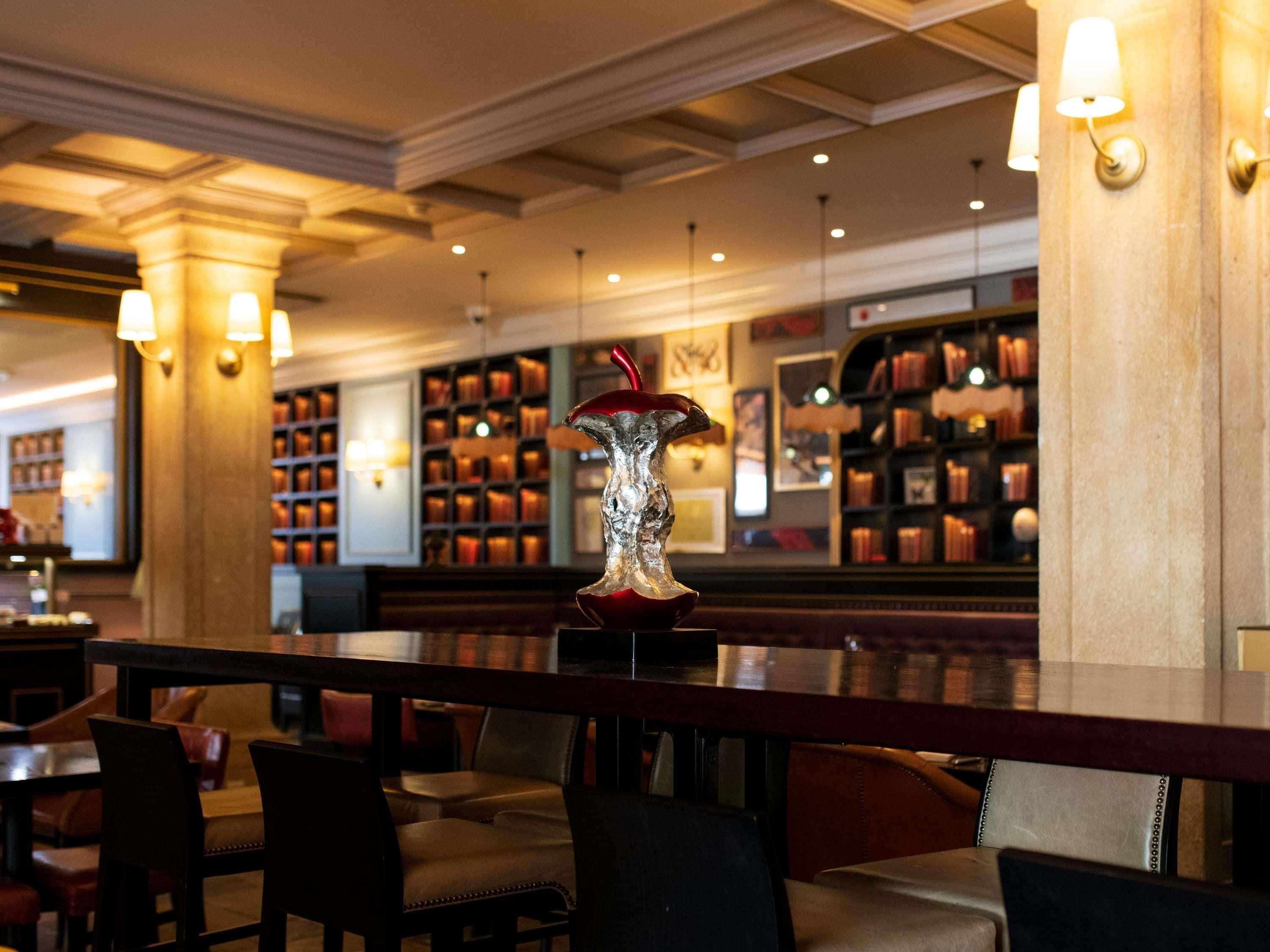 Een bar met een decoratieve glazen vaas als middelpunt, boekenkasten en zitplaatsen.