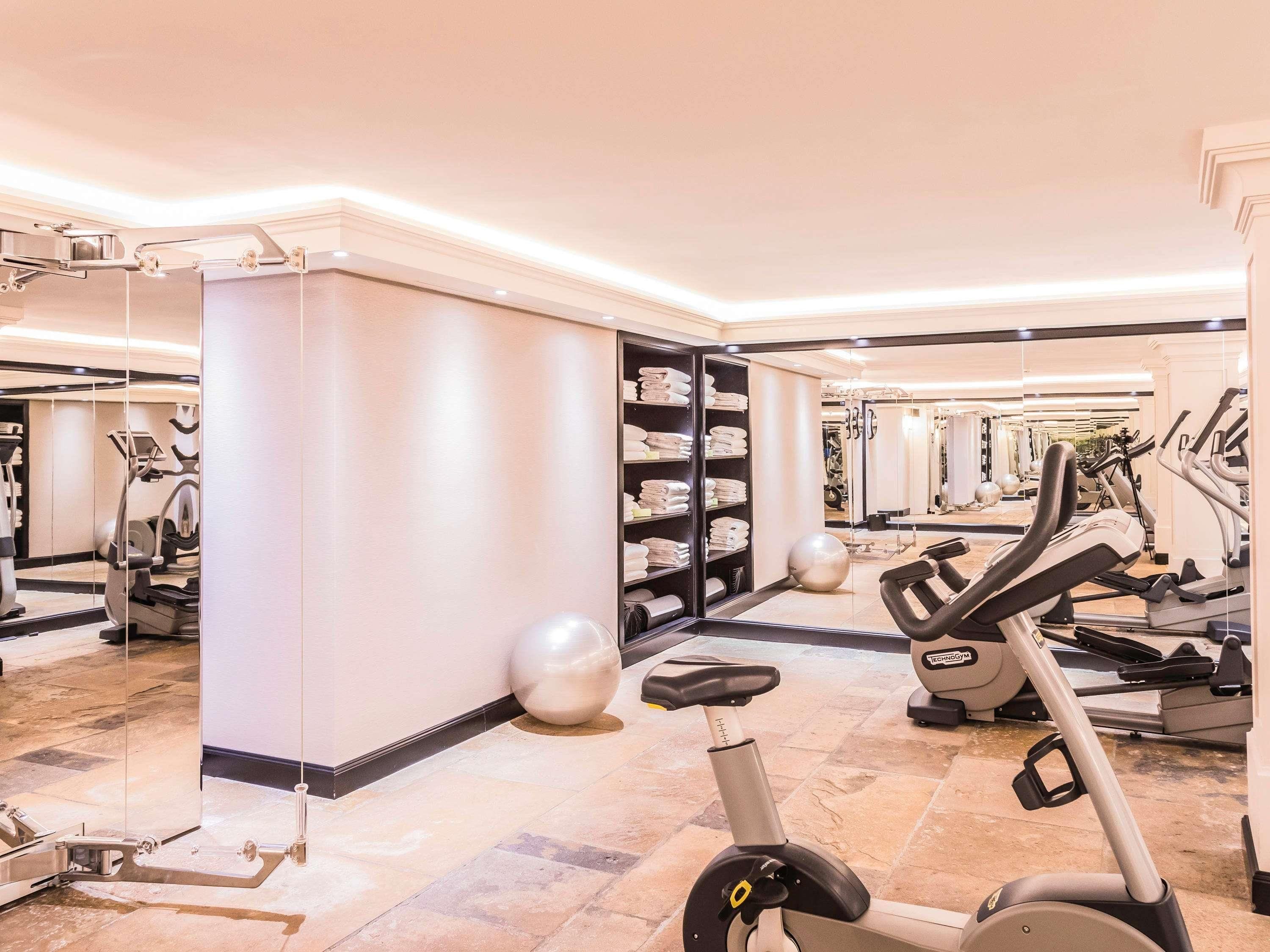 A gym with exercise equipment, a mirrored wall, and a storage area with towels.
