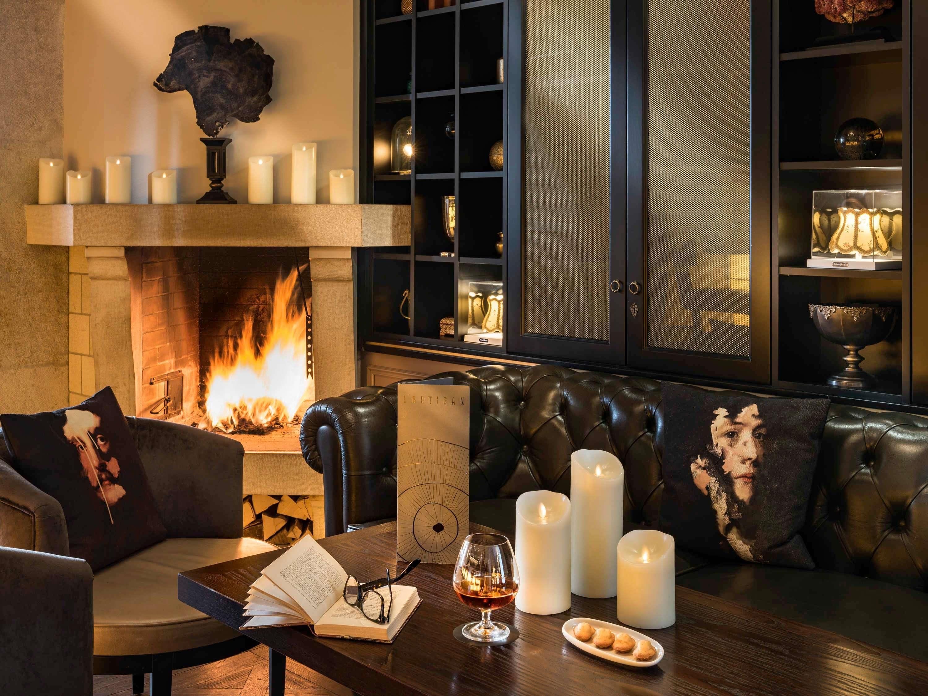 Ein gemütliches Wohnzimmer mit Kamin, Ledersofas und einem Couchtisch mit Buch, Gläsern und einem Glas Wein.