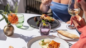 Una mesa de comedor con platos de comida, vasos y cubiertos.