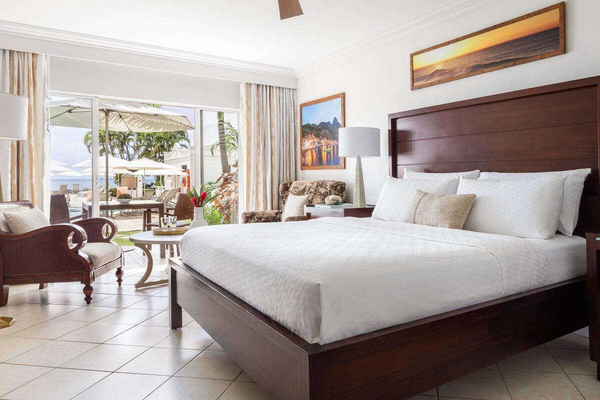 Une chambre d’hôtel spacieuse, dotée d’un grand lit, d’un bureau, d’une chaise et offrant une vue sur l’espace extérieur.