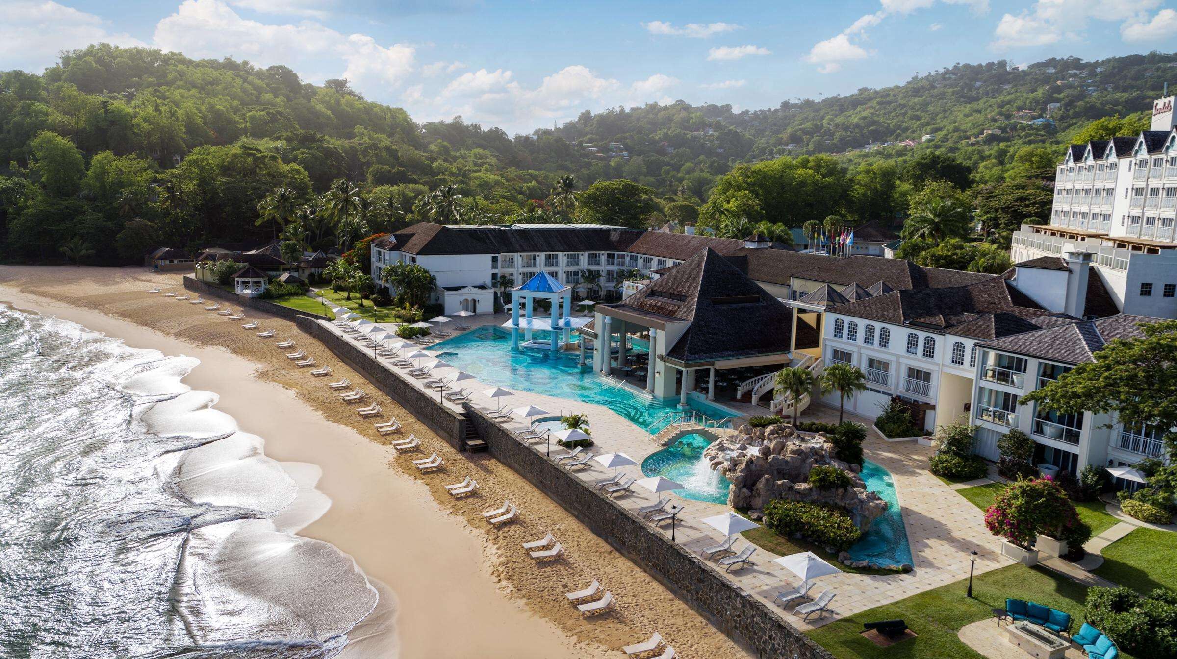 A resort with a large pool, beach, and mountain views.