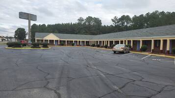 Ein Motel mit einer Reihe von Zimmern, einem Parkplatz und einer großen, leeren Werbetafel.