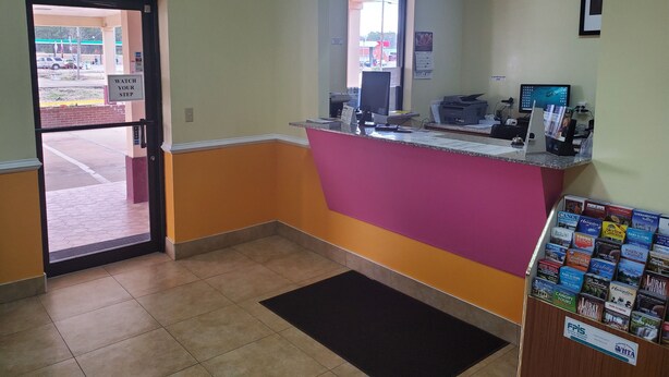 A reception area with a counter, a computer, and a window.