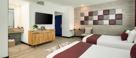 Una habitación de hotel moderna con dos camas, un armario de madera, un televisor y un panel decorativo en la pared.