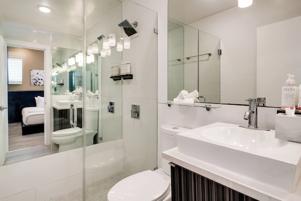 A modern bathroom with a glass shower enclosure, a large mirror, and a white sink.