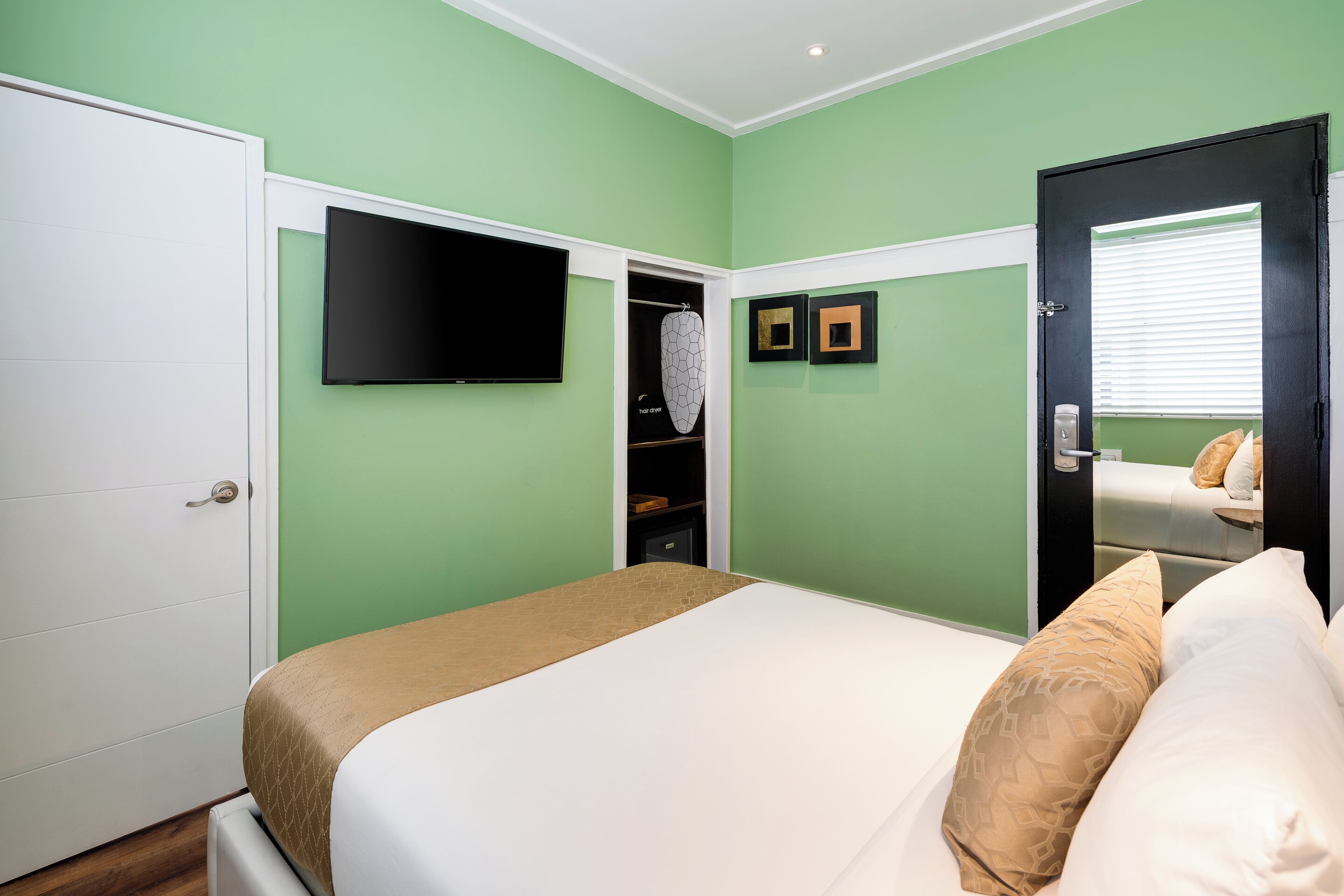 A bedroom with a bed, a television, a wardrobe, and a door.