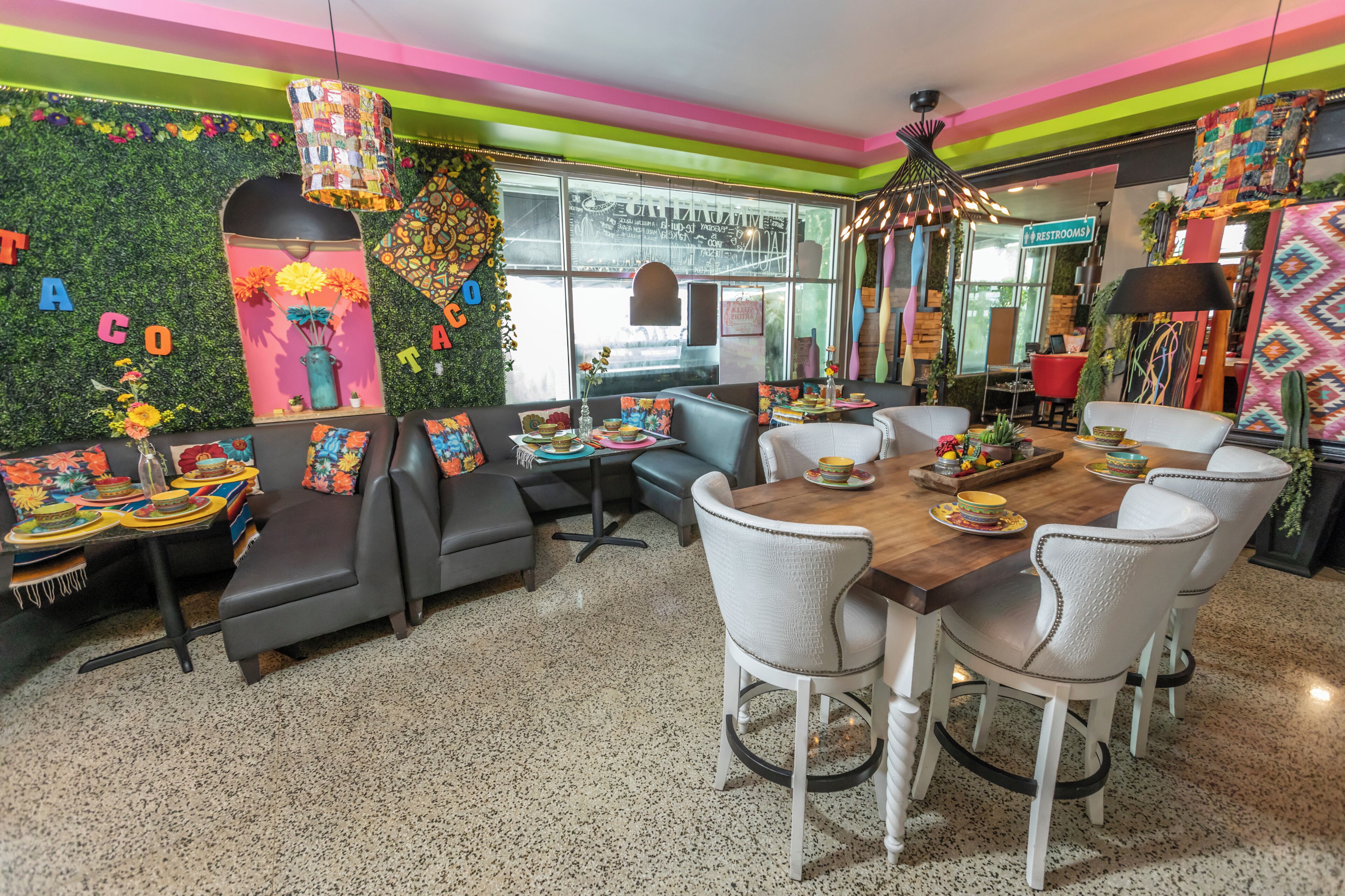 A vibrant dining area with a wooden table, white chairs, and colorful decor.