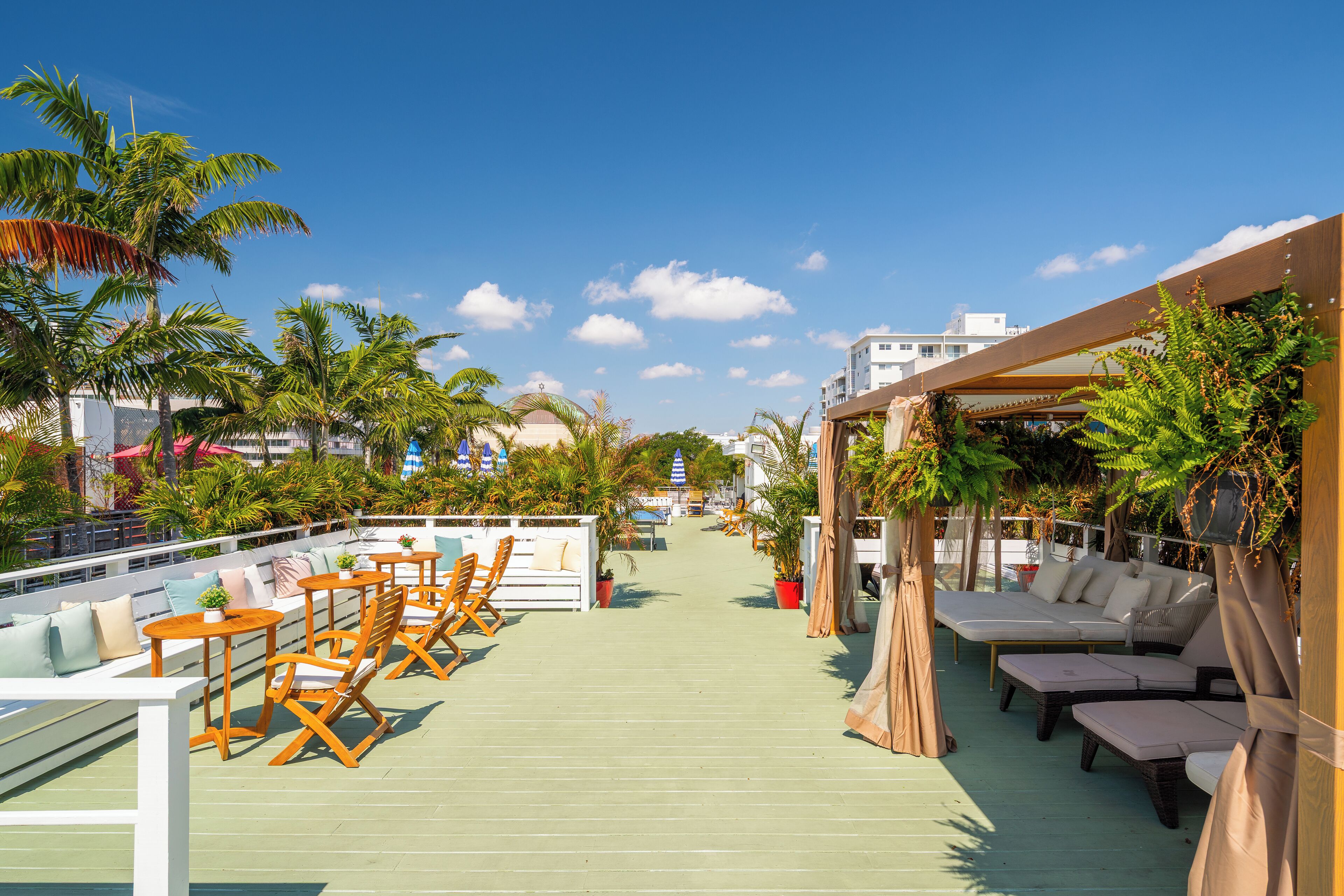 A rooftop deck with wooden lounge chairs and a pool.