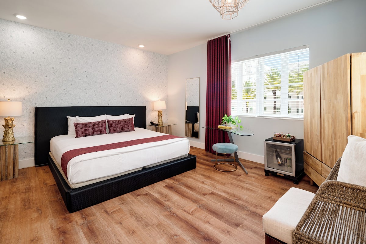 Une chambre moderne avec un grand lit, une petite table de chevet, une chaise, une armoire et une fenêtre avec des rideaux.