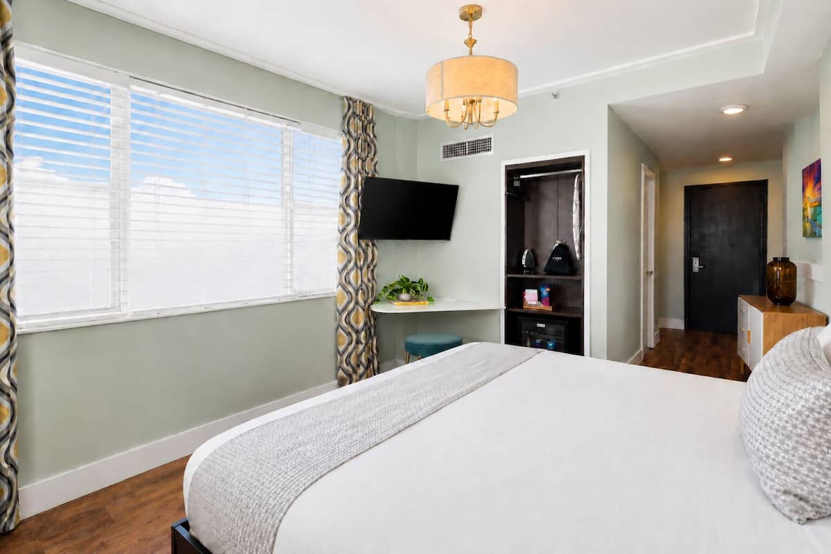 Une chambre à coucher avec un lit, une télévision, un bureau et une armoire.