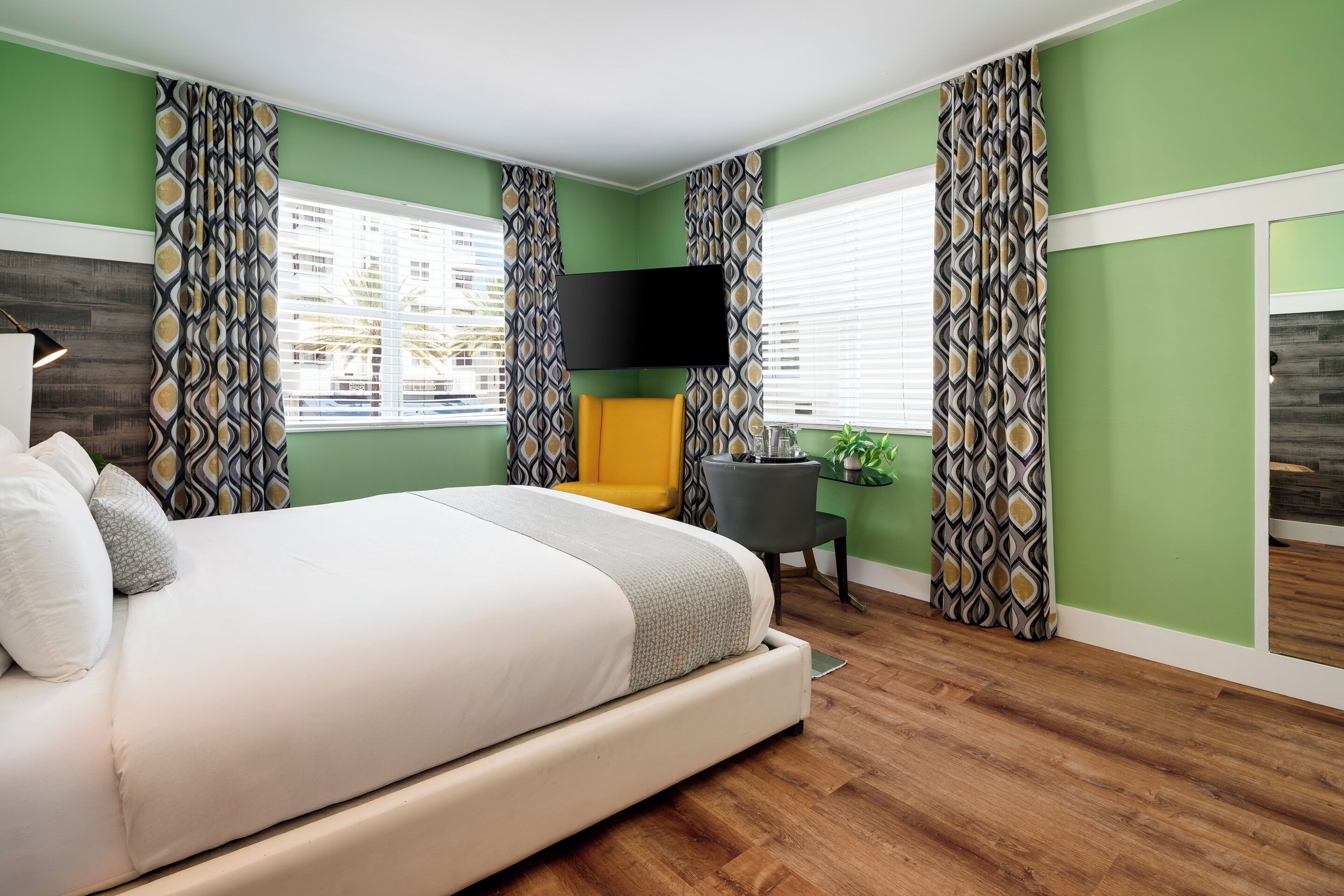 Un dormitorio moderno con una cama grande, un escritorio y un televisor.